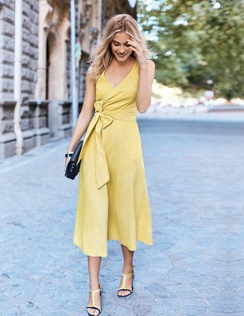 Picture Of a stylish yellow linen midi wrap dress with a bow on .