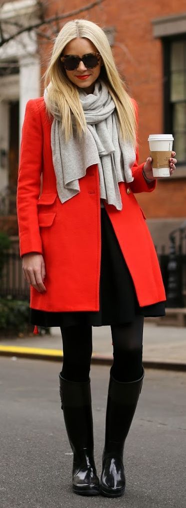 bright coat contrasted against black tights and gray scarf .