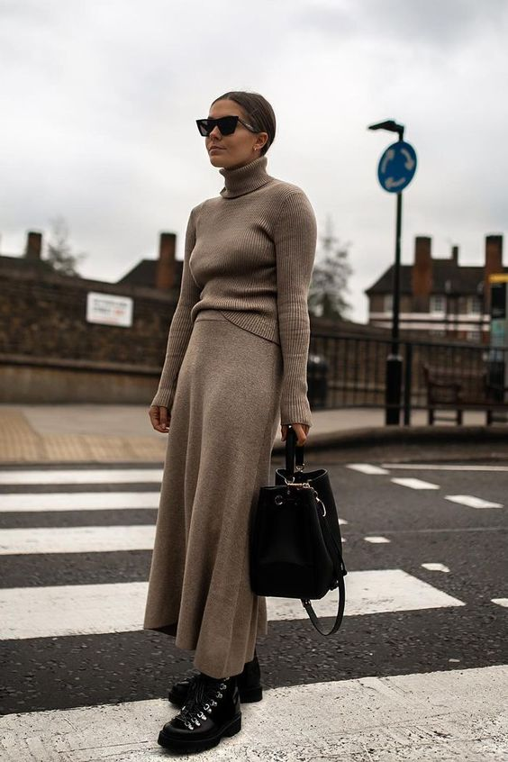 a tan knit suit with an A line midi skirt, black hiking boots and .