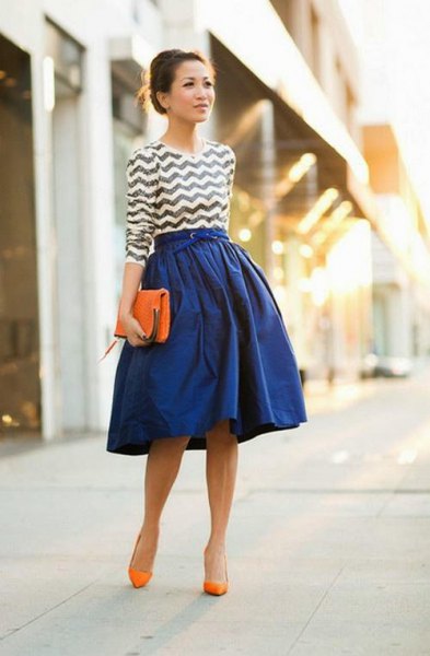 black and white patterned top with a royal blue flared skirt and orange heels