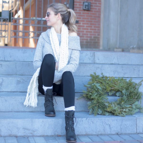 gray one-shoulder sweater with black leggings and lace-up boots