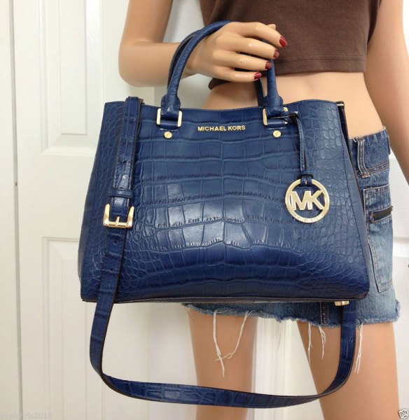 Dark blue leather handbag with a green crop top and mini shorts