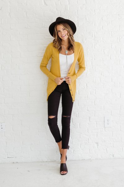 mustard yellow cardigan with black felt hat and ripped jeans