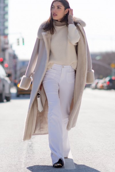 Blush pink wool coat with faux fur collar and flared white jeans