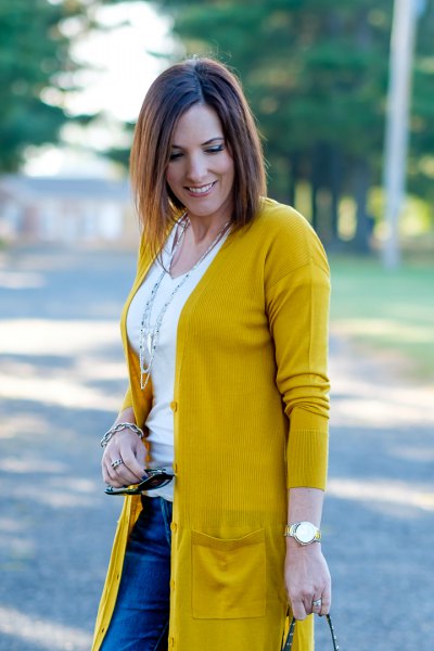 Mustard yellow knit sweater with white scoop neck t-shirt and blue jeans