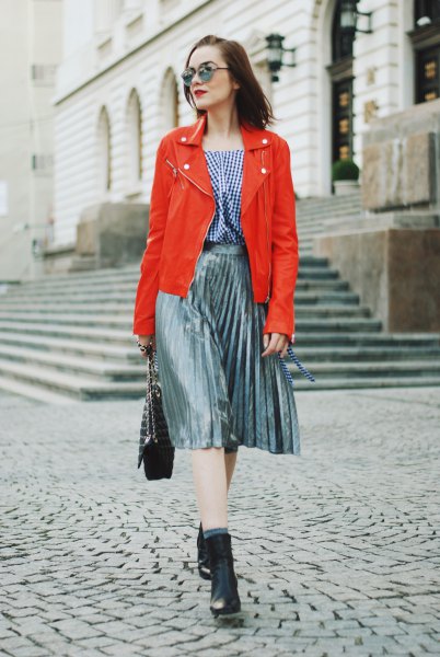 orange leather jacket with plaid blouse and silver pleated skirt