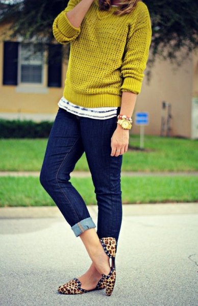 Mustard yellow sweater with dark blue skinny jeans with cuffs and flat shoes with animal print