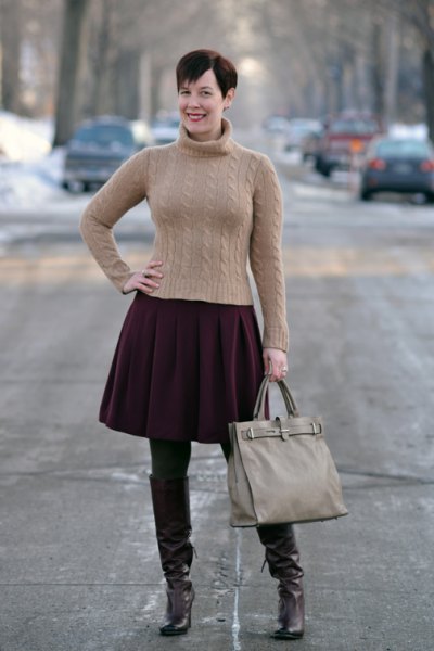 Figure-hugging green turtleneck with black pleated skirt and brown tights