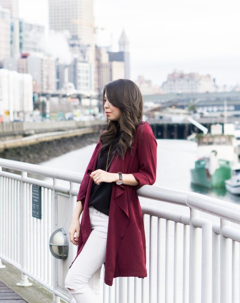 Burgundy trench coat with a black sweater and white skinny jeans