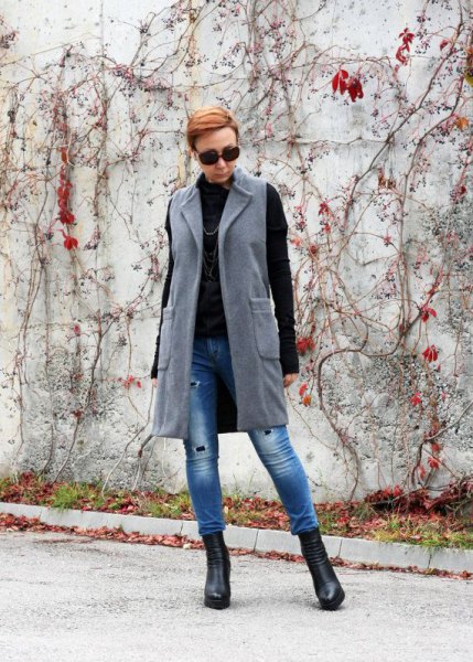 gray longline wool vest with blue drainpipe jeans and black sweater