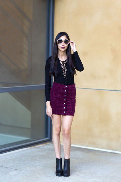 Figure-hugging blouse with a neckline and a black corduroy mini skirt with a button placket