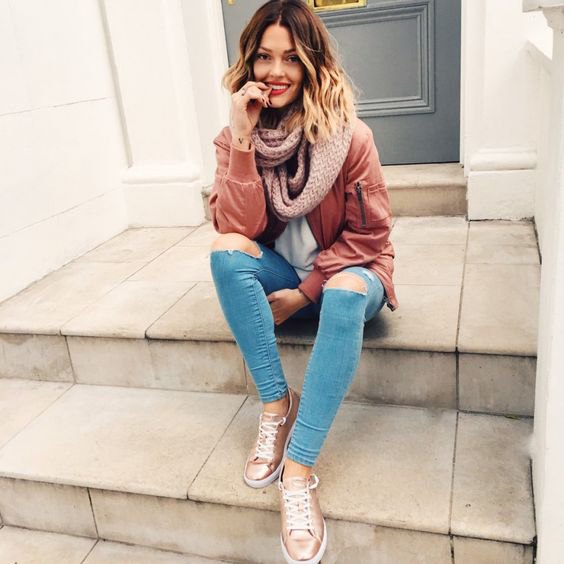 Blush pink bomber jacket with light blue skinny jeans and gold sneakers