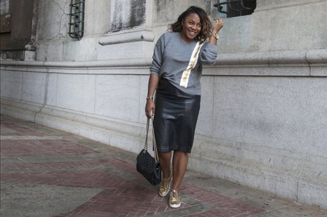 gray sweater with black midi leather skirt and gold low-top sneakers