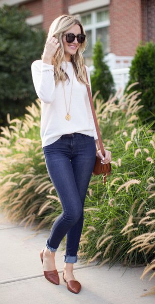 white sweater with a round neckline and dark blue skinny jeans with cuffs