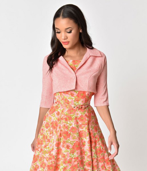Light pink short sleeve cropped jacket worn with a red floral midi dress