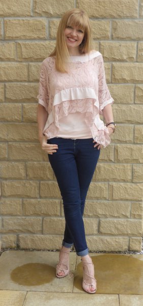 Blushing blouse with half-sleeved lace neckline and dark blue skinny jeans with cuffs