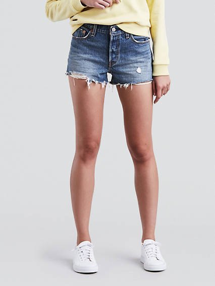 Light yellow chunky sweatshirt with blue Levis jean shorts and white sneakers