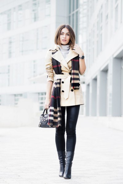 beige trench coat with belt and black and white plaid scarf