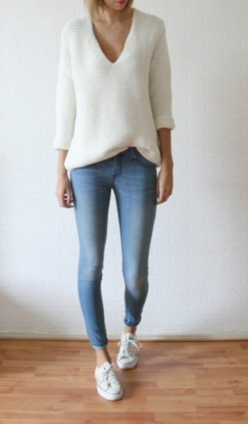 White relaxed fit V-neck knit sweater paired with light blue skinny jeans