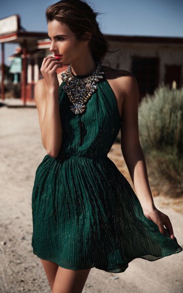 green halterneck mini dress with gathered waist and statement chain