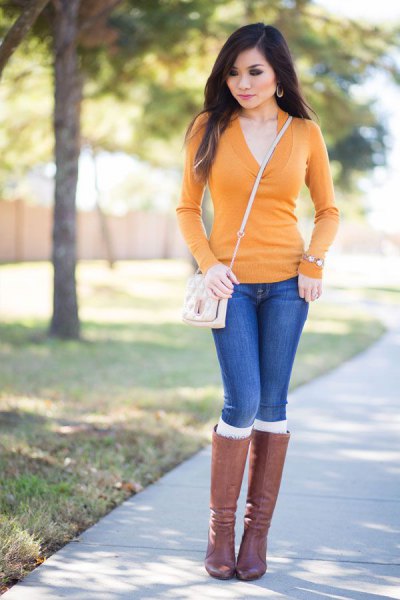 Mustard V-neck fitted sweater, blue jeans and gray knee high boots