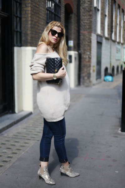 Light pink oversized knitted one shoulder sweater and black cropped maternity jeans