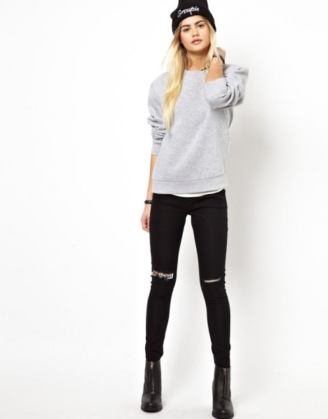gray sweatshirt with ripped black skinny jeans and knit hat