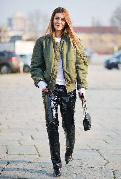 green satin bomber jacket with white sweater and black leather pants