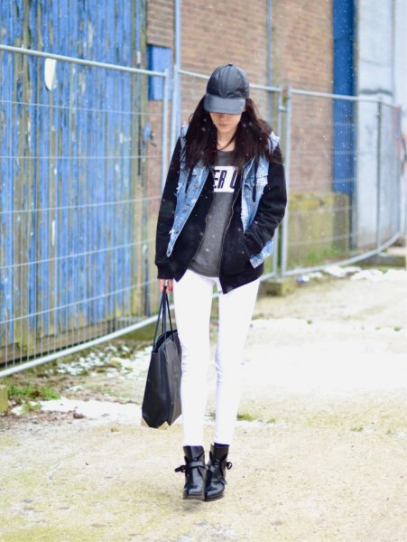 black leather baseball cap with denim vest and graphic sweater