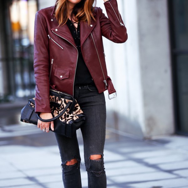 Burgundy leather jacket with black shirt and ripped skinny jeans