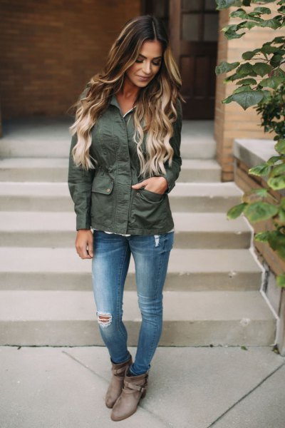 gray hiking jacket with blue ripped slim fit jeans and boots