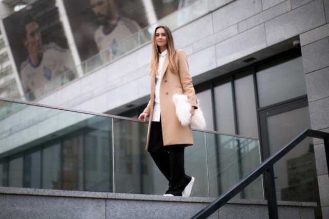 Blush pink longline wool coat with black trousers and white faux fur clutch handbag