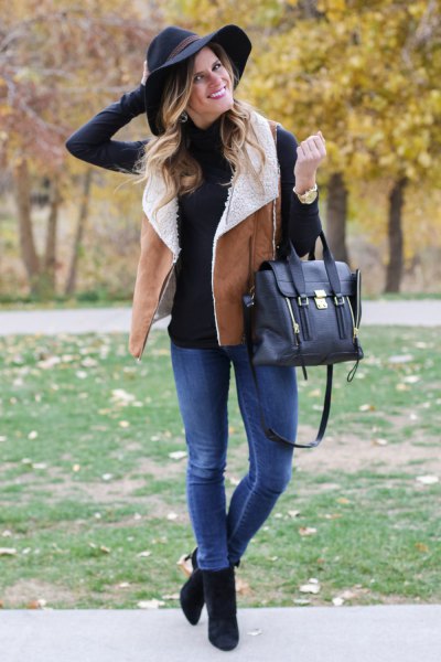 black mock-neck sweater with camel lambskin vest and blue jeans