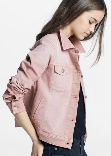 Light pink denim jacket worn with a deep V-neck black tank top and wide leg jeans