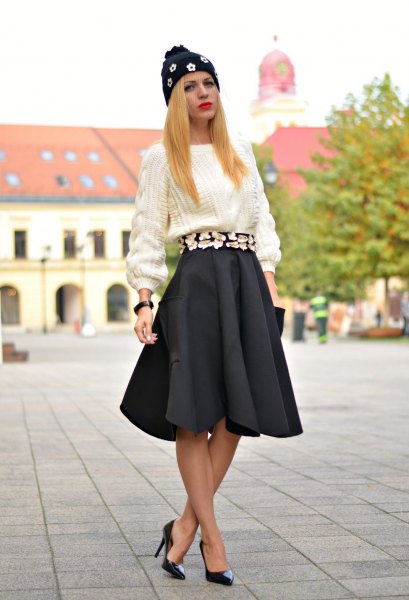 white chunky knit sweater with black pleated skirt and heels