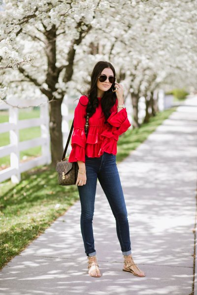 Skinny jeans with a red ruffled blouse and cuffs