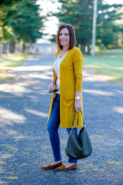 Mustard yellow longline cardigan with a white waistcoat top and blue jeans