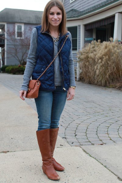 blue quilted vest with gray long sleeve top and brown knee high boots