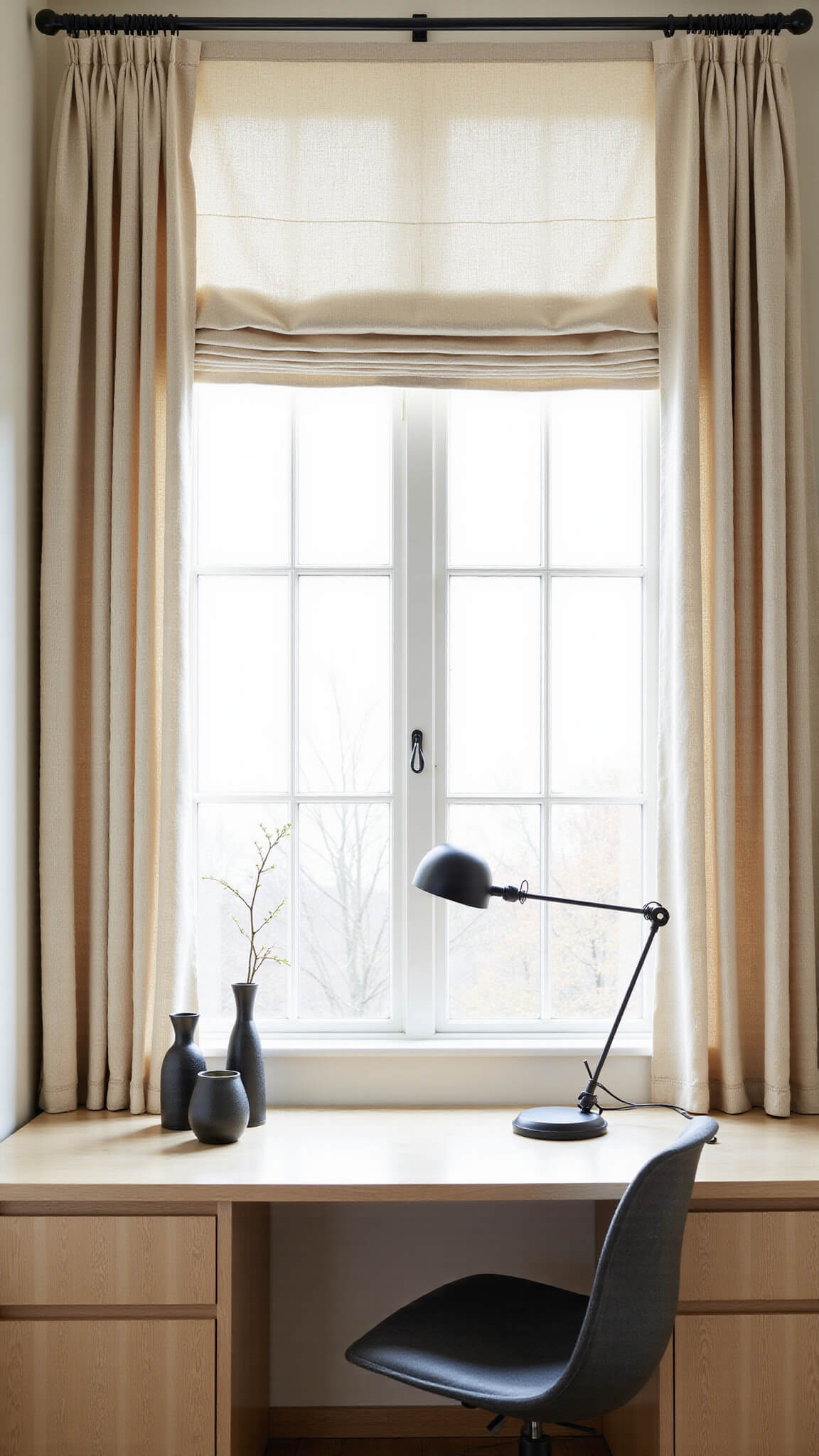 Compact Japandi-inspired home office with ivory cotton curtains, built-in pale ash wood desk, black task lamp, ceramic accents, and an orchid basking in morning sunlight.