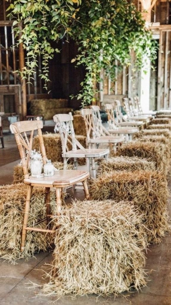 Rustic seating arrangement with hay bales and elegant decor in a barn setting.