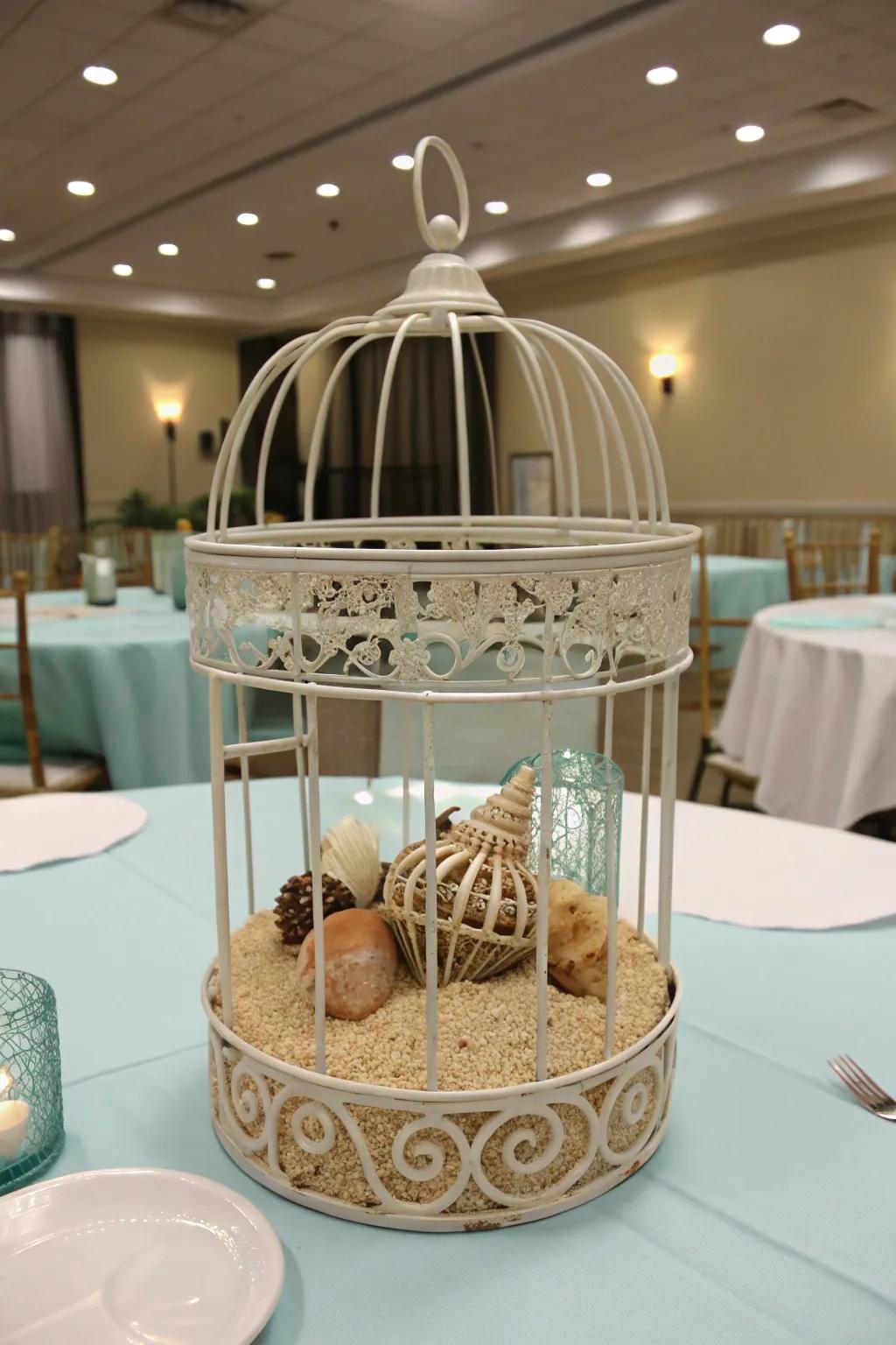 Bird cage centerpiece featuring seashells and sand for a beachy vibe.