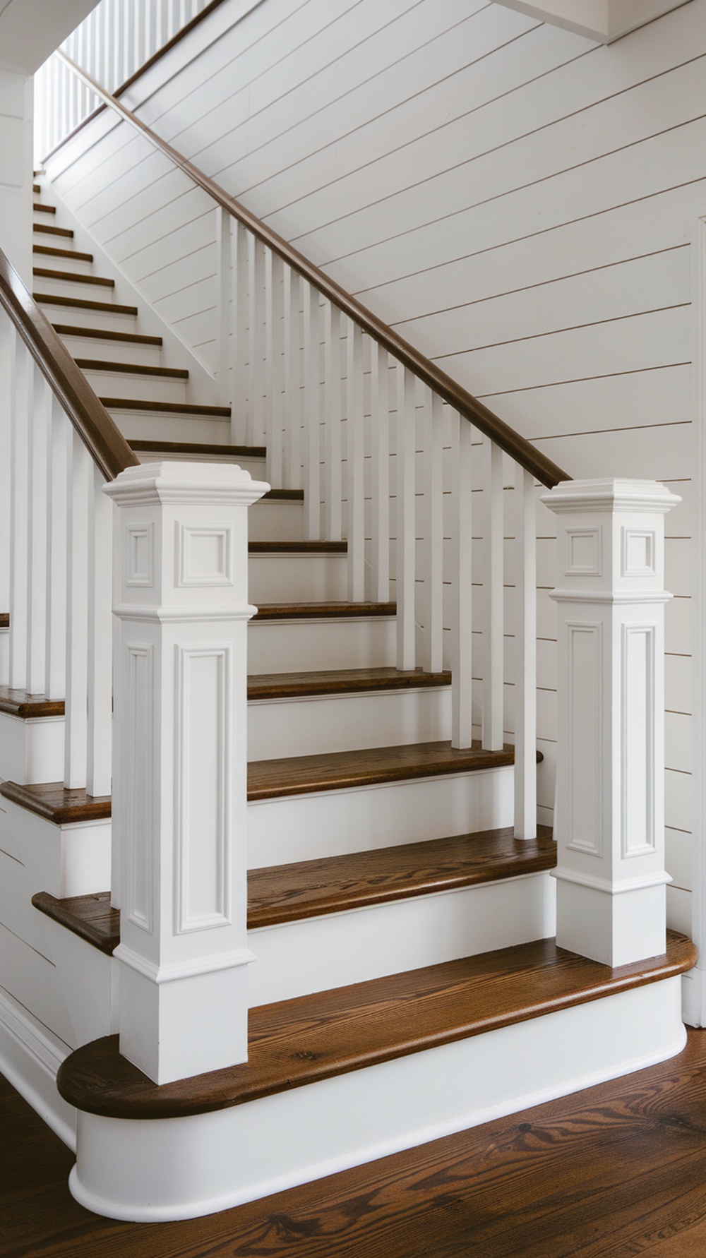 A modern farmhouse staircase featuring white railings and wooden steps.